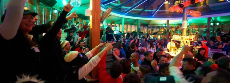 Guests dancing and enjoying après-ski festivities at Schirmbar Sonne in Sölden, Austria, featuring lively music and a vibrant alpine party atmosphere Guests dancing and enjoying après-ski festivities at Schirmbar Sonne in Sölden, Austria, featuring lively music and a vibrant alpine party atmosphere