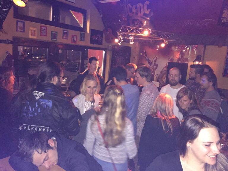 Patrons enjoying live rock music and drinks at Little Rock bar in Innsbruck, Austria, immersed in a vibrant atmosphere with rustic decor and a curated selection of classic rock, metal, and blues tracks
