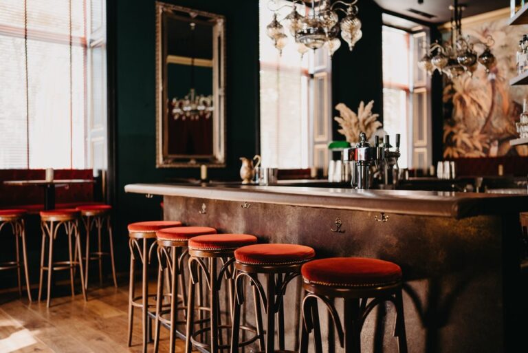 Interior of Liquid Diary cocktail bar in Innsbruck, Austria, featuring an open-plan layout with imperial design elements, ambient lighting, and a central bar area, creating a stylish and inviting atmosphere for guests