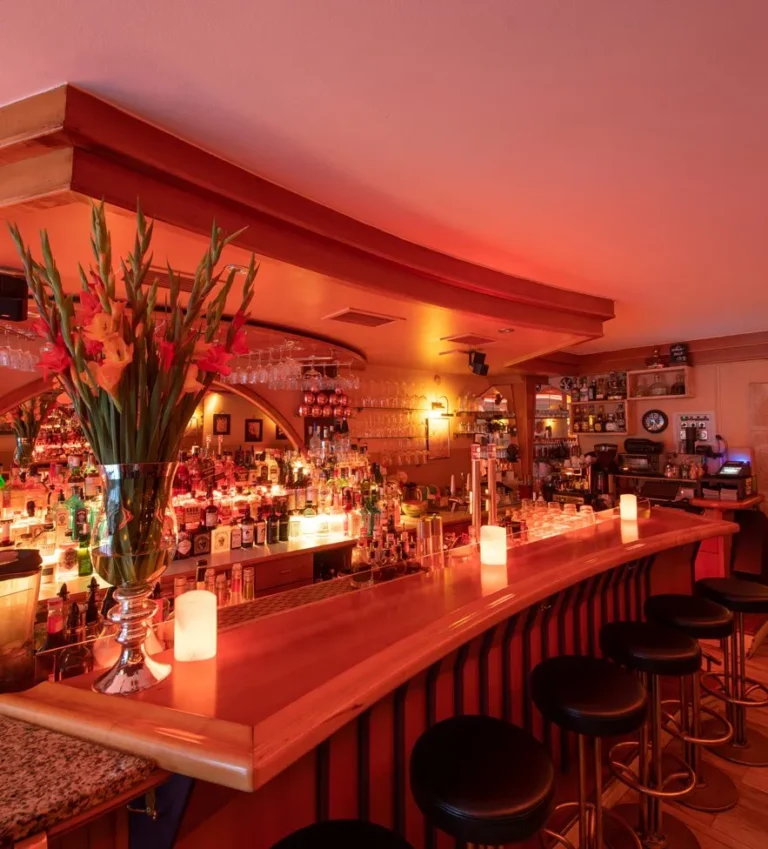 Bar area of M+M Cocktailbar in Innsbruck, Austria, featuring a sleek, illuminated counter with a wide selection of spirits and over 150 cocktails, creating a stylish and inviting atmosphere for cocktail enthusiasts