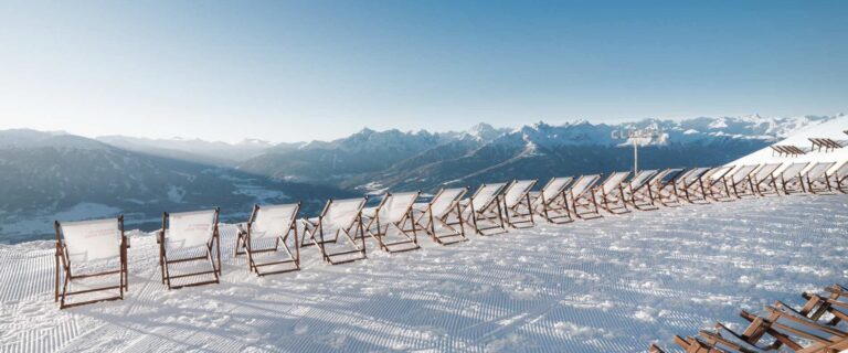 Panoramic mountain view from Cloud 9 Sun Terrace in Innsbruck, Austria, showcasing the majestic Nordkette Alps under a clear blue sky, with snow-covered peaks and the city of Innsbruck visible below