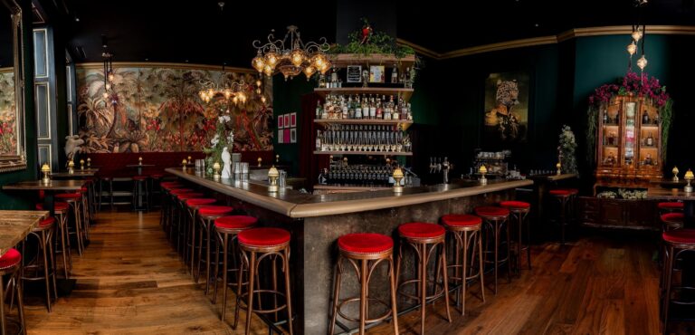 Bar area of Liquid Diary in Innsbruck, Austria, featuring a sleek, illuminated counter with mosaic tiles, high stools, and a well-stocked selection of spirits, creating a stylish and inviting atmosphere for cocktail enthusiasts