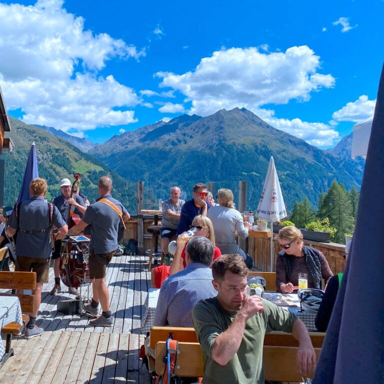Guests reveling in the lively après-ski atmosphere at Eugen’s Obstlerhütte in Sölden, Austria, featuring live music, traditional Tyrolean hospitality, and a festive alpine setting
